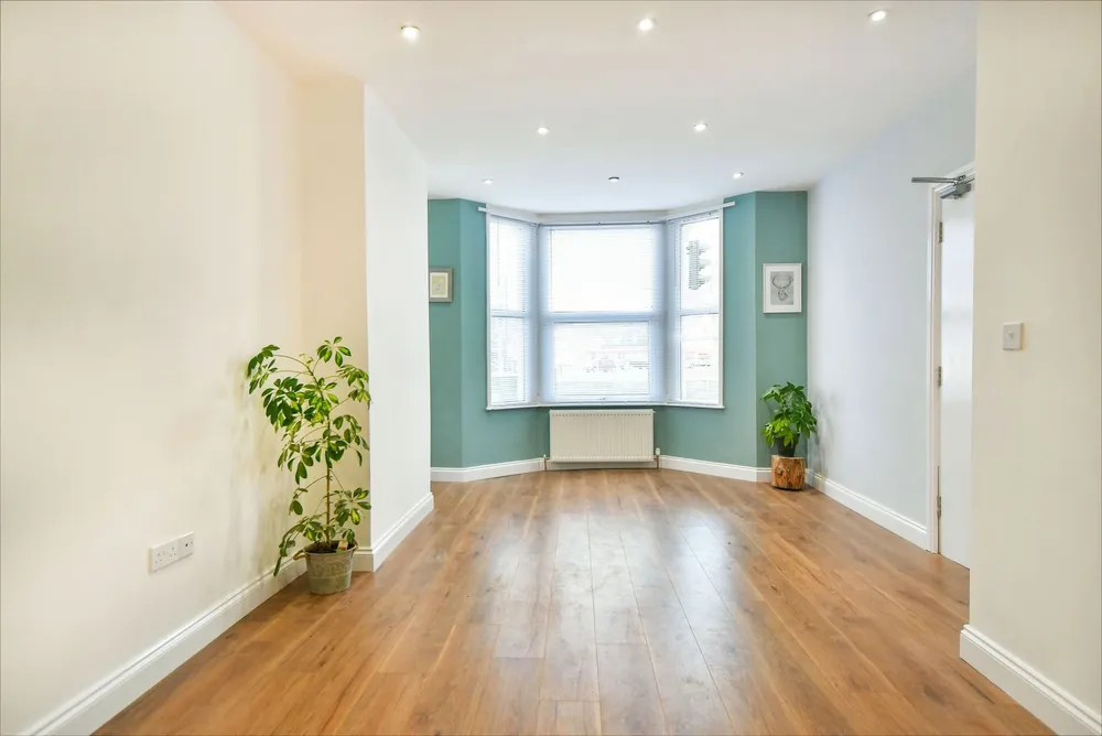 A bright bay-windowed room with new wooden floors
