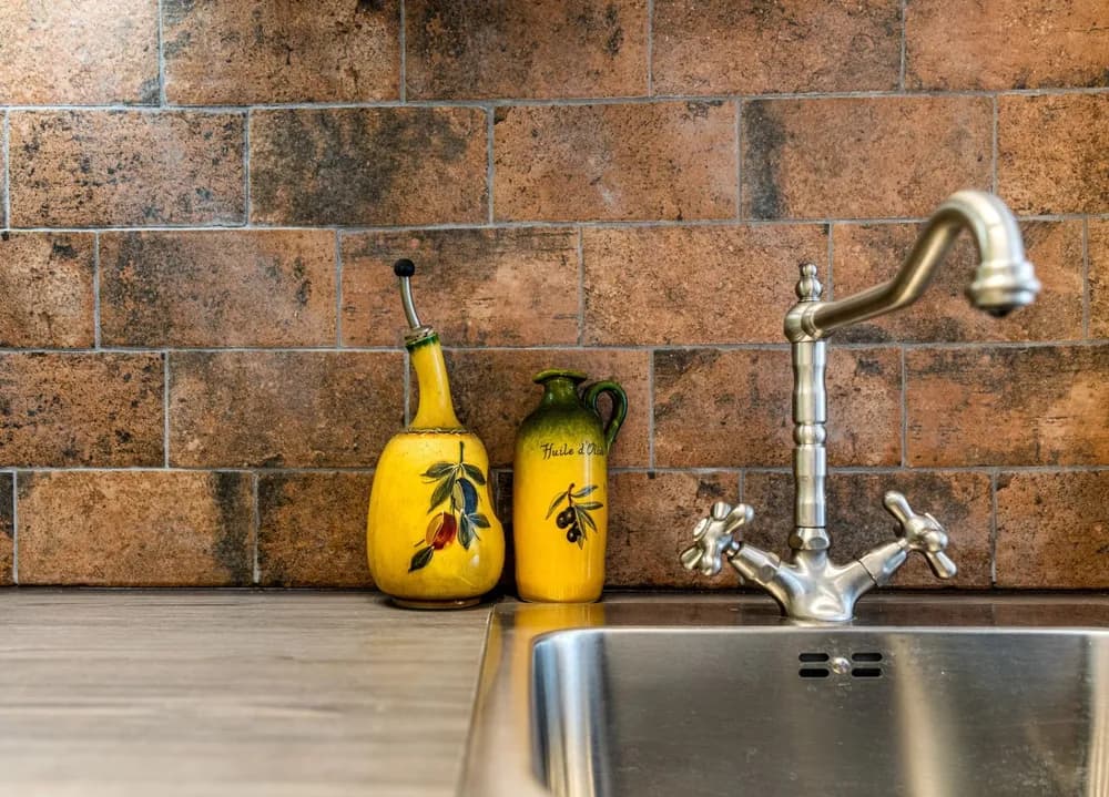 A studio kitchen with brick-effect tiles and a brass tap