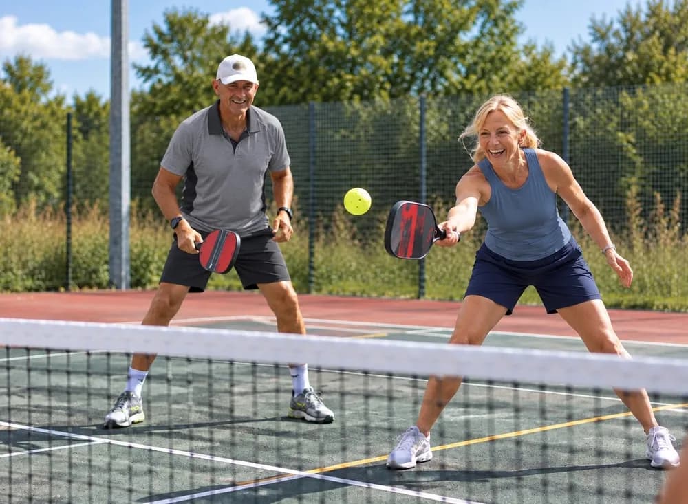 Two Newbury Pickleball players rallying at the net